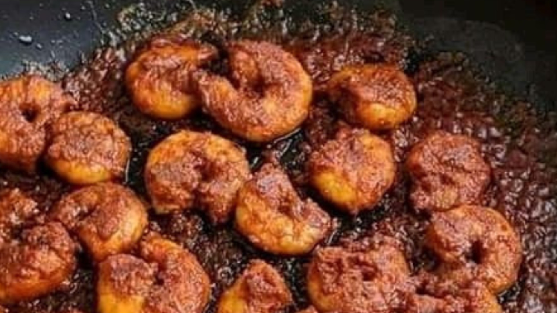 Golden vadas frying in a pan of hot oil in a Kokan kitchen