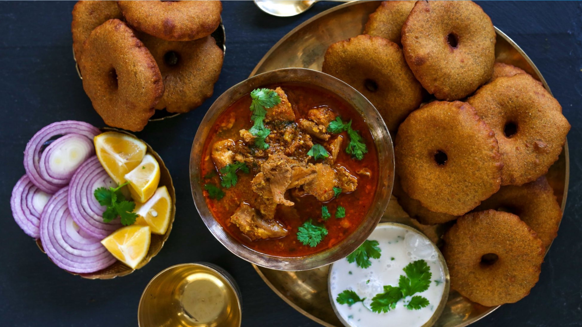 Plate of vadas served with spicy Kokan mutton rassa, onion and lemon